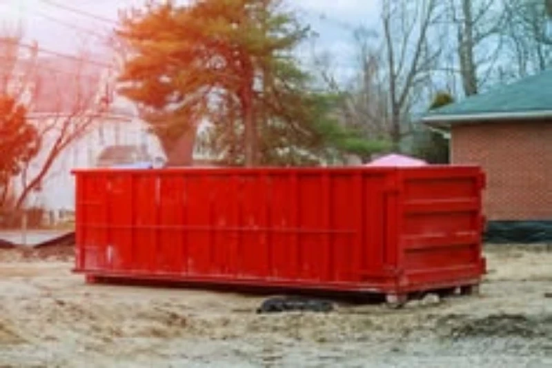 A red dumpster sitting on bare ground.