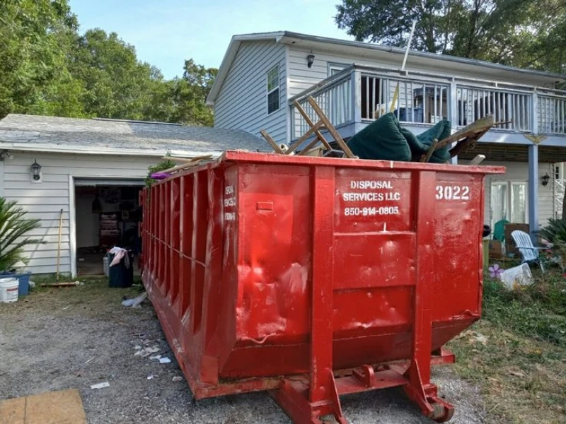 Red dumpster with “Disposal Services LLC” outside a blue house, trees in the background.