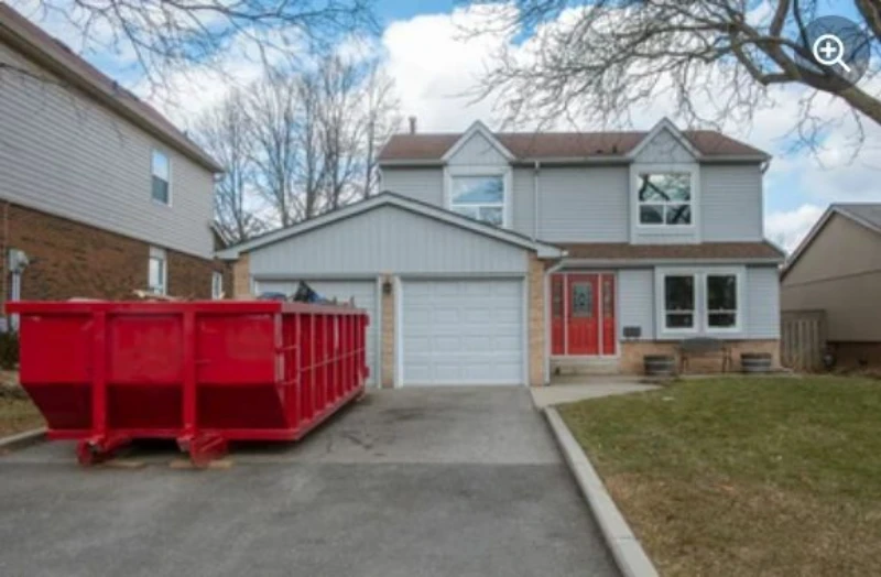 A two-story house with a red dumpster in the driveway.